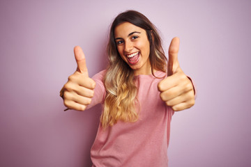 Young beautiful woman wearing a sweater over pink isolated background approving doing positive...