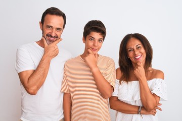 Family of three, mother, father and son standing over white isolated background looking confident at the camera with smile with crossed arms and hand raised on chin. Thinking positive.