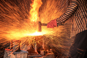 Blacksmith forging the molten metal with a hammer to make keris