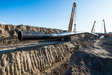Gas pipeline construction. Heavy duty construction machines placing gas pipe into the ground.