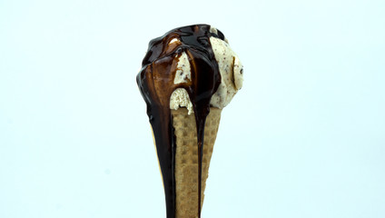 Chocolate sauce on scoop Ice cream cookies & Cream in waffle cone on White background, Closeup Front view Food concept..