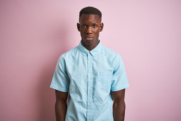 African american man wearing blue casual shirt standing over isolated pink background skeptic and nervous, frowning upset because of problem. Negative person.