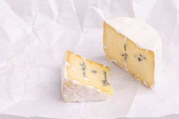 Blue cheese with white surface, isolated on white background, soft light, studio photo. Mix of gorgonzola and camembert / brie cheese.