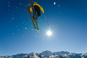 Skier Jumping Through Blue Sky and Sun with Distant Mountains