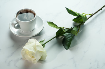 Obraz na płótnie Canvas coffee background of a cup of hot black coffee with bunch of white rose on white marble background