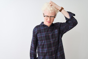 Young albino blond man wearing casual shirt and glasses over isolated white background confuse and wonder about question. Uncertain with doubt, thinking with hand on head. Pensive concept.