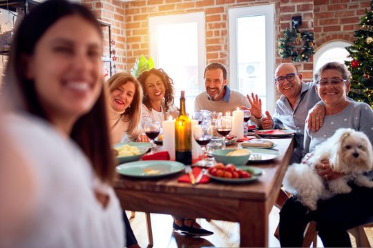 Family and friends dining at home celebrating christmas eve with traditional food and decoration, taking a selfie picture together