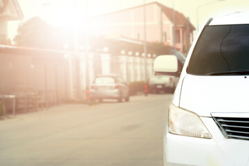 Front of white car on the road in the city of residence with sunset.