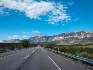 Asphalt road in the mountains with soft sky on the background.