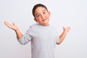 Beautiful kid boy wearing grey casual t-shirt standing over isolated white background clueless and confused expression with arms and hands raised. Doubt concept.