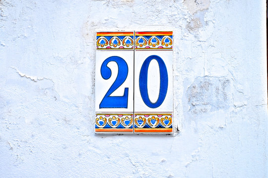 Number 20, twenty, old colorful tiles on white aged wall.