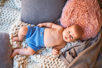 Adorable baby lying down on the sofa over blanket at home. Newborn relaxing and resting comfortable