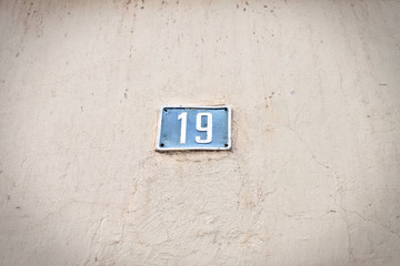Number 19, nineteen, pale blue plate on light cream background, slight vignette effect.