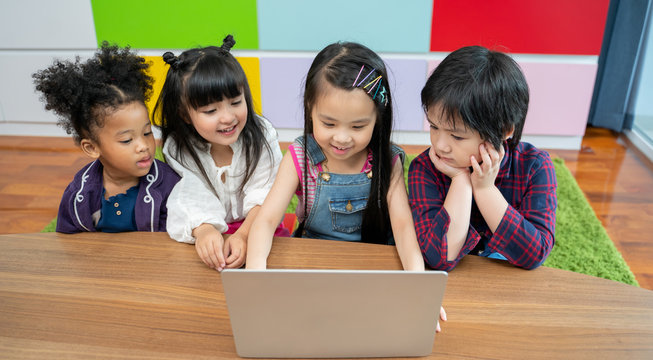 group of little children diversity watching film together on laptop. Kids playing with laptop computer at home