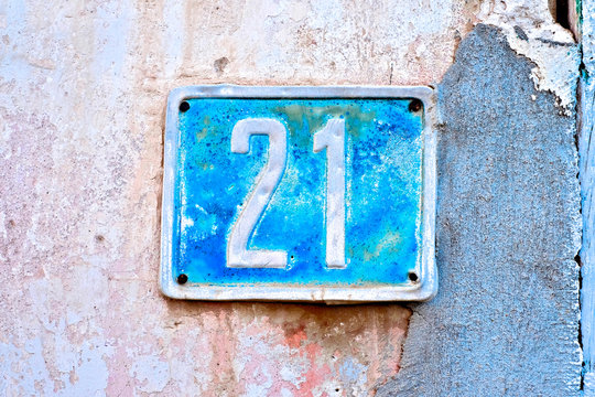 Number 21, twenty-one, old number plate on a weathered wall.