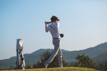 Side view, Asian Man hiting golf ball on the golf course in summer. sport, golfer concept.