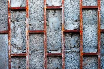 Rusty bars over gray concrete blocks, an abstract fragment of old abandoned building.