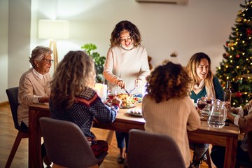 Beautiful group of women smiling happy and confident. Carving roasted turkey celebrating christmas at home