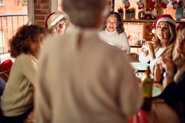 Beautiful group of women smiling happy and confident. On of them holding cup of wine speaking speech celebrating christmas at home