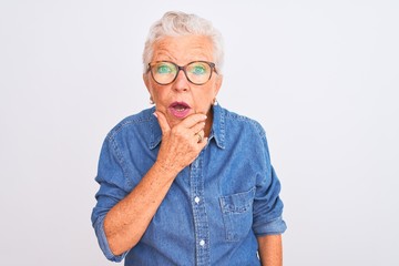 Senior grey-haired woman wearing denim shirt and glasses over isolated white background Looking...