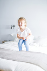 Naklejka premium Beautiful. toddler child girl jumping on the bed