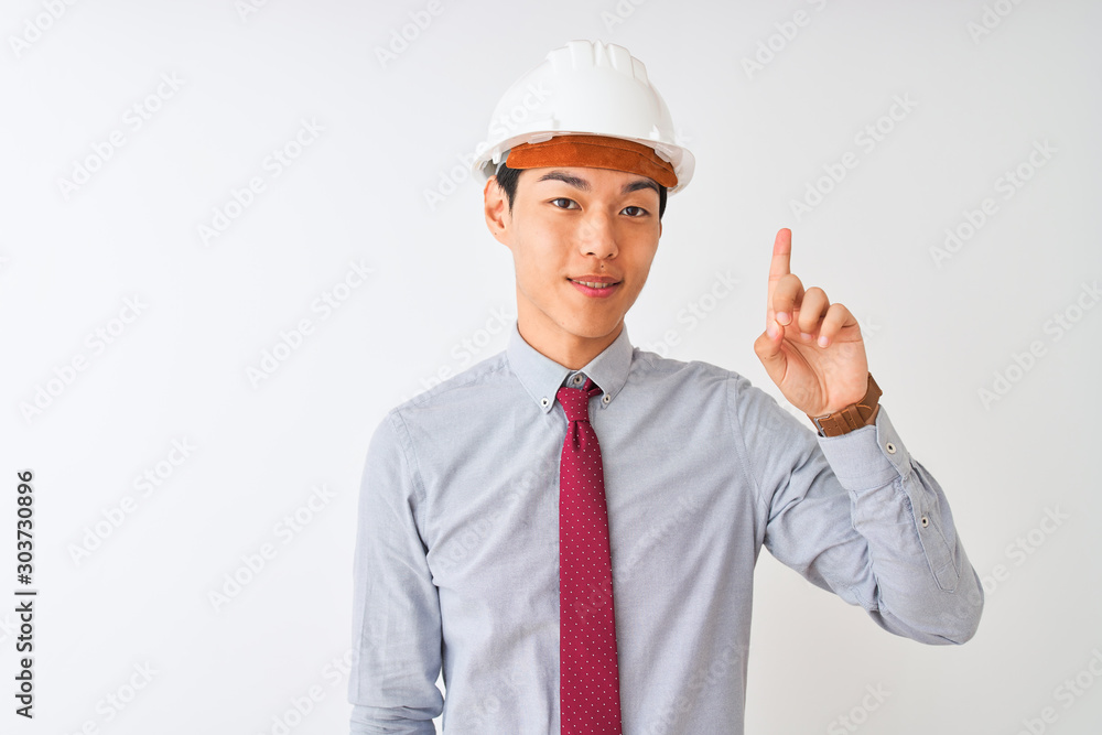 Poster Chinese architect man wearing tie and helmet standing over isolated white background showing and pointing up with finger number one while smiling confident and happy.