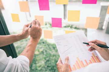 Business people meeting at office and use sticky notes on glass wall in office, diverse employees...