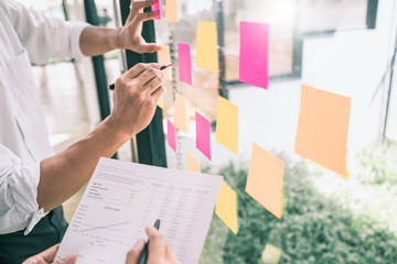 Business people meeting at office and use sticky notes on glass wall in office, diverse employees people group planning work together brainstorm strategy.