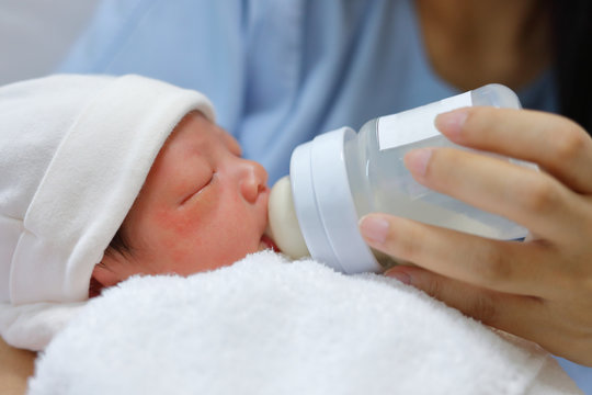 little newborn baby sucking milk in bottle