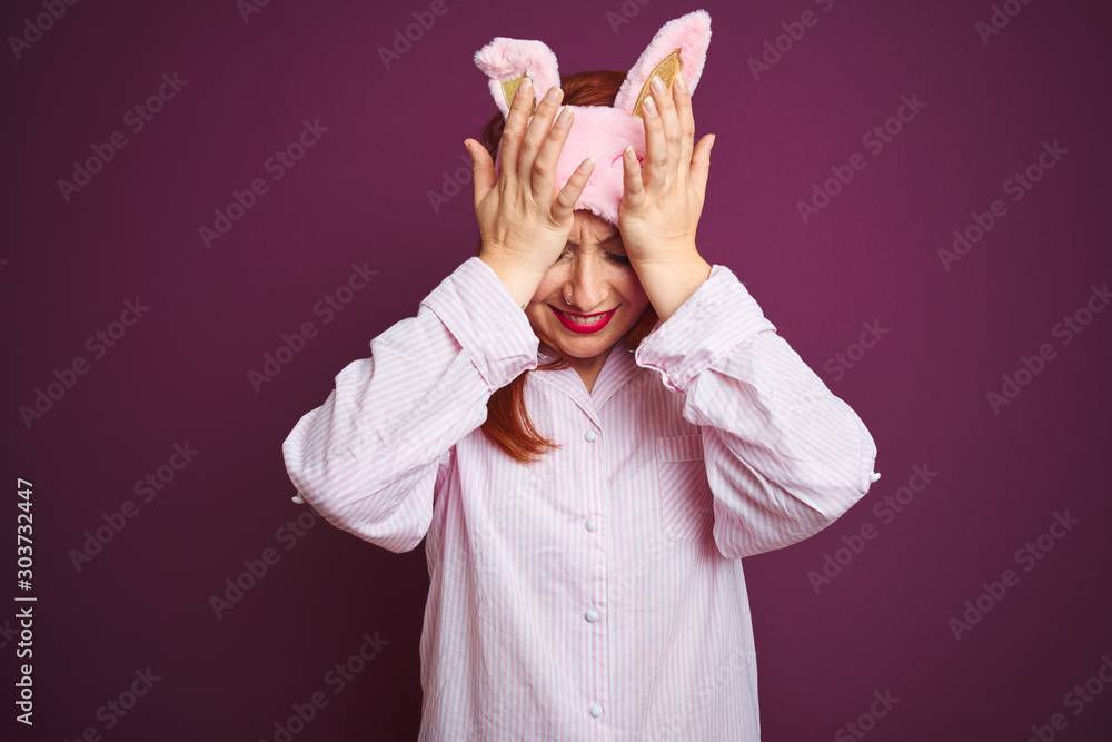 Canvas Prints Young beautiful redhead woman wearing pajama and mask over purple isolated background suffering from headache desperate and stressed because pain and migraine. Hands on head.