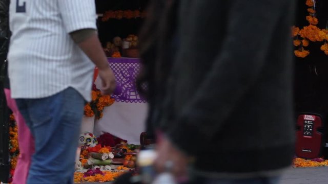 close up of people walking by the altar during day of the dead celebration in mexico, taking pictures