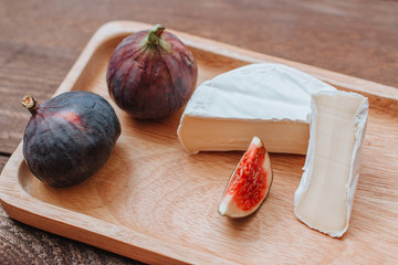 Camembert cheese and fresh figs on a wooden plate