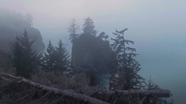 Aerial: flying over foggy calm ocean and rocky islands at sunset. Brookings, Oregon, USA