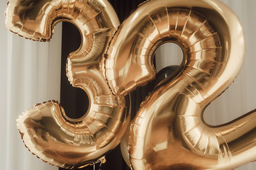 decor for the holiday. gold foil balloons, numbers 32 against the background of black curtains,...