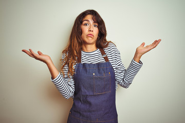 Young beautiful chef woman wearing apron cooking over white isolated background clueless and...