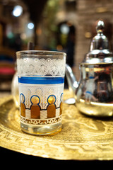 tasty half full glass with black tea or coffee on golden tray with silver pot ordered in teahouse in Cordoba, Spain, Europe