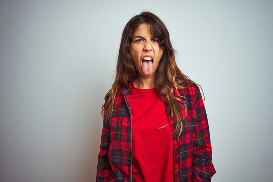 Young beautiful woman wearing red t-shirt and jacket standing over white isolated background sticking tongue out happy with funny expression. Emotion concept.