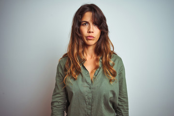 Young beautiful woman wearing green shirt standing over grey isolated background skeptic and nervous, frowning upset because of problem. Negative person.