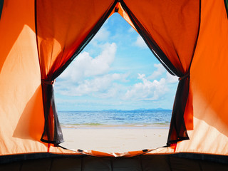 opening door of orange tent camping over summer beach background.