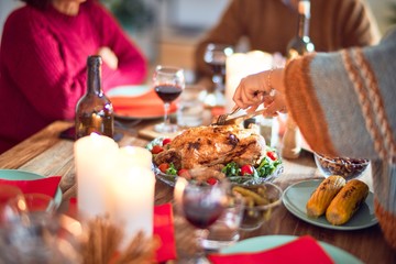 Beautiful family smiling happy and confident. One of them curving roasted turkey celebrating thanksgiving day at home