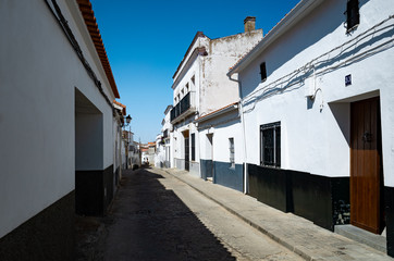 Fototapeta na wymiar Zafra, Spain - March 27 2019: Typical spanish / andalusian black and white B&W village street, with ancient charming houses, Andalusia, Spain, Europe, blue sky