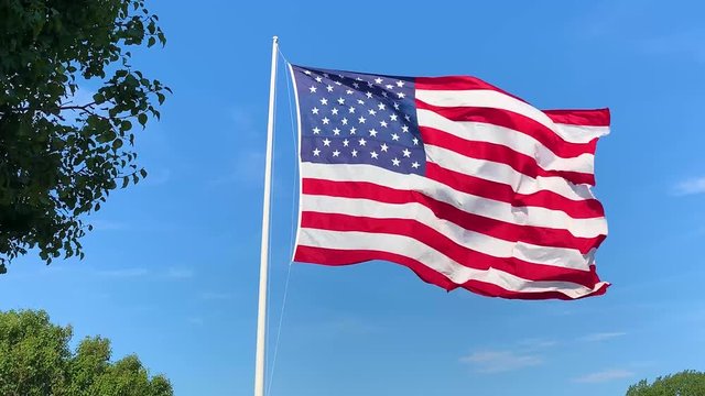 American Flag waving in the wind against blue sky.