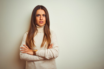 Young beautiful woman wearing winter turtleneck sweater over isolated white background skeptic and nervous, disapproving expression on face with crossed arms. Negative person.