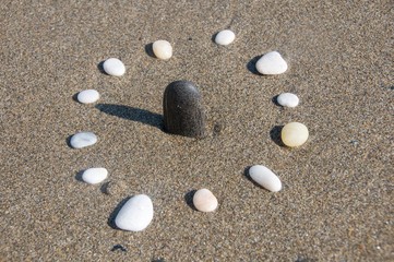 Fototapeta na wymiar Natural sun dial. Pebbles and sandy beach 