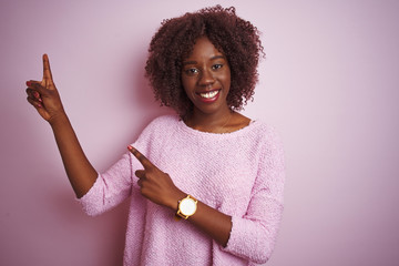 Young african afro woman wearing sweater standing over isolated pink background smiling and looking...