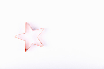 Flatlay with star copper cookie cutter on white sparkling background. Holiday, Christmas and New Year concept. Cozy homey details. Flat lay, top view background. Horizontal