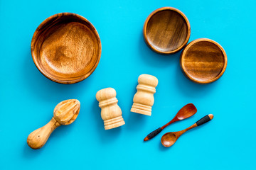 Set of rustic wooden tableware - bowls and utensils on blue background top view