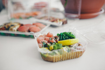 Japanese cuisine: fish, lemon, onion, avocado in a plastic container. Advertising concept of traditional Oriental cuisine