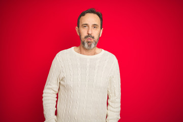 Obraz premium Handsome middle age senior man with grey hair over isolated red background puffing cheeks with funny face. Mouth inflated with air, crazy expression.