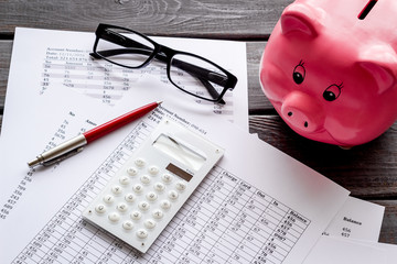 Taxes payment concept. Financial documents, piggy bank, calculator on dark wooden background